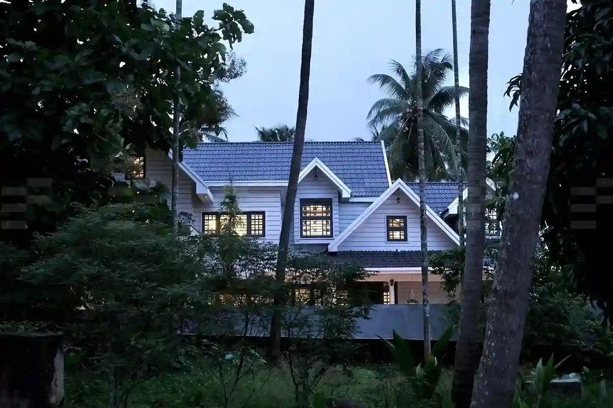 Side elevation of Kerala colonial house design at night, featuring glowing verandas, traditional columns, and tiled roofing.
