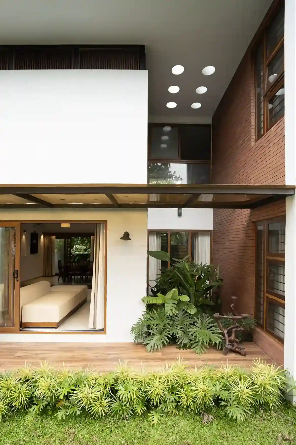 Covered outdoor patio and deck connecting to the open living space, showcasing the wooden accents and indoor plants.