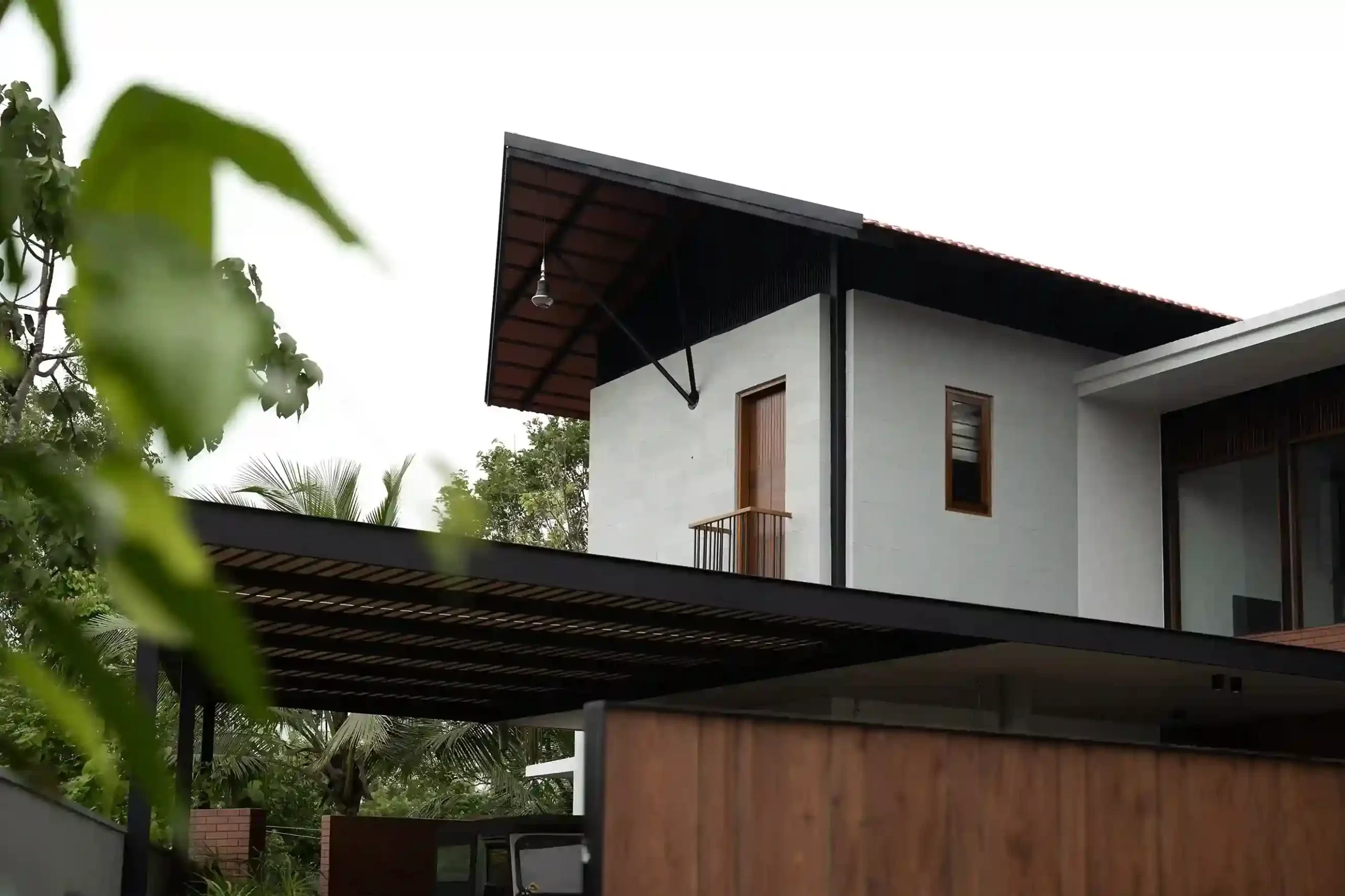 Corner view showing the traditional sloped roof section and the flat roof over the metallic slatted car porch structure.