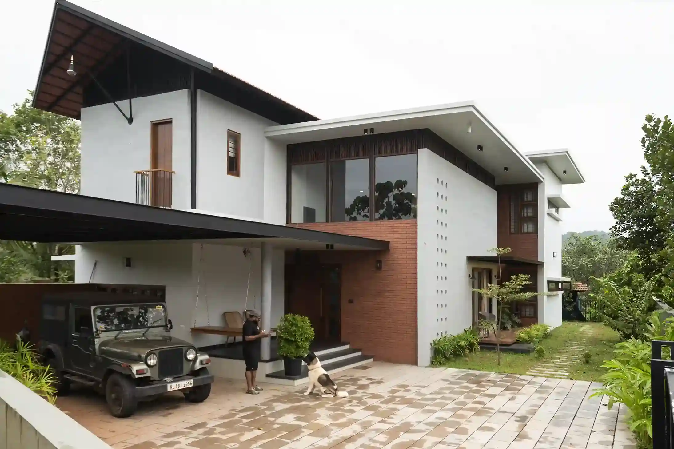 KYMARA: Main exterior view of the Tropical Modern house in Pulikkal, Kerala, featuring the white facade, brick cladding, and covered car porch.